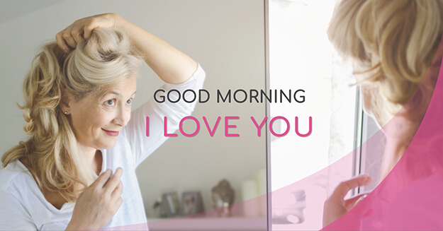 A woman looking in a mirror while holding her hair back with the words Good morning, I love you.