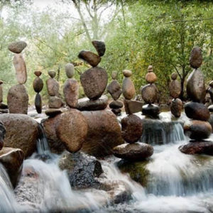 Rocks stacked so that they balance on top of each other in the middle of a stream.